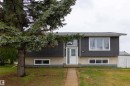 Split-level residence featuring a white entry door with frosted glass, dark horizontal siding, and a light-colored foundation - 4004 88 Street, Edmonton, AB 