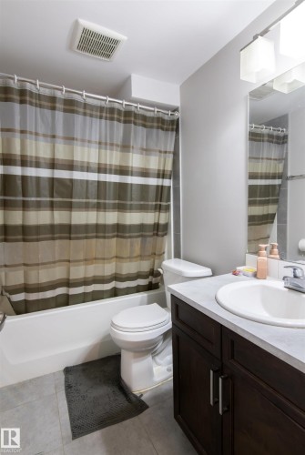 Bathroom featuring a dark wood-finish vanity with a light countertop, an undermount sink, and a mirrored wall - 4004 88 Street, Edmonton, AB 