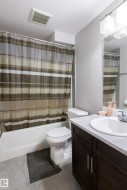 Bathroom featuring a dark wood-finish vanity with a light countertop, an undermount sink, and a mirrored wall - 