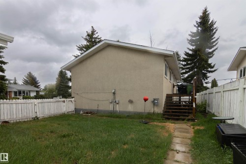 Rear exterior featuring stucco siding, white trim, and a wood deck - 4004 88 Street, Edmonton, AB 