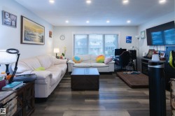 Spacious living area featuring wood-finish flooring, recessed lighting, and a prominent window - 