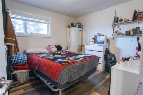 Bedroom featuring wood-finish flooring, a white-framed window, and white walls - 4004 88 Street, Edmonton, AB 