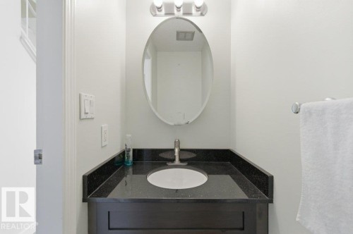 Powder room featuring a dark wood-finish vanity with a black speckled countertop and an undermount sink - 13279 47 Street, Edmonton, AB - Indoor Photo Showing Bathroom
