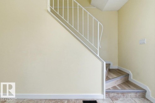 Staircase featuring wood-finish treads and risers, white metal railing, and white baseboards - 13279 47 Street, Edmonton, AB - Indoor Photo Showing Other Room