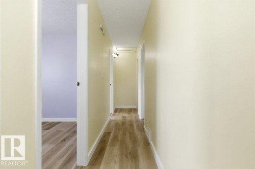 Hallway featuring wood-finish flooring, light-colored walls, white baseboards, and a ceiling-mounted light fixture - 13279 47 Street, Edmonton, AB - Indoor Photo Showing Other Room