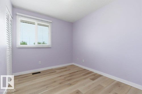 Interior room featuring light purple walls, wood-finish flooring, white baseboards, and a window with white blinds - 13279 47 Street, Edmonton, AB - Indoor Photo Showing Other Room