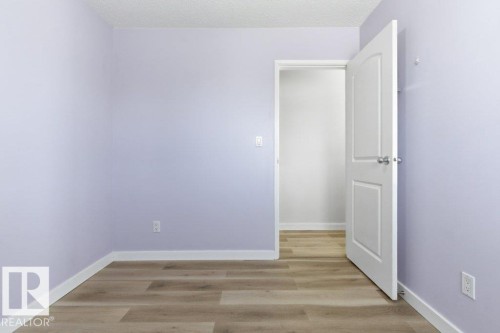 Room featuring light wood-finish flooring, light purple walls, white trim, and a white interior door with a silver knob - 13279 47 Street, Edmonton, AB - Indoor Photo Showing Other Room