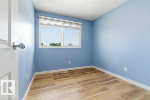 Room featuring wood-finish flooring, a window with horizontal blinds, and light blue walls with white trim - 13279 47 Street, Edmonton, AB - Indoor Photo Showing Other Room