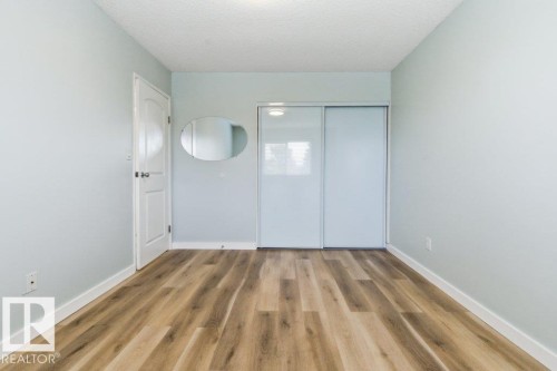 Spacious room featuring wood-finish flooring, light blue wall paint, white baseboards, and a white ceiling - 13279 47 Street, Edmonton, AB - Indoor Photo Showing Other Room
