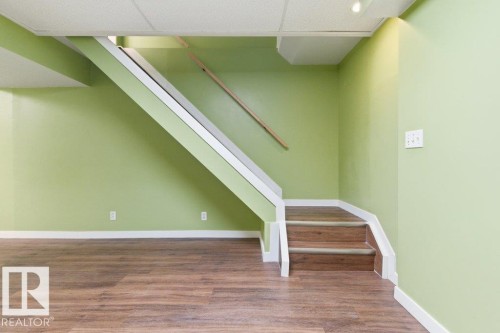 Staircase with wood-finish treads and white risers, featuring a wood handrail - 13279 47 Street, Edmonton, AB - Indoor Photo Showing Other Room