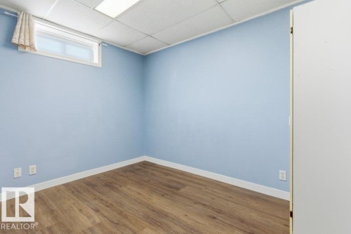 Room featuring light blue walls, wood-finish flooring, a white drop ceiling with recessed lighting, and a window with white trim - 13279 47 Street, Edmonton, AB - Indoor Photo Showing Other Room