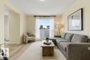 Light-filled living area featuring wood-finish flooring, neutral wall tones, a large picture window with privacy glass, and a wide entryway - 13279 47 Street, Edmonton, AB  - Indoor Photo Showing Living Room 