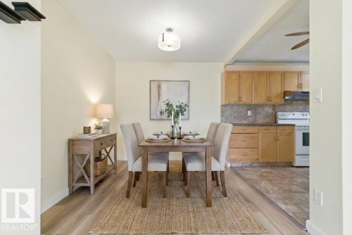 Dining area with wood-finish flooring featuring a rectangular light wood table, four upholstered chairs, and a contemporary ceiling fixture - 13279 47 Street, Edmonton, AB - Indoor Photo Showing Dining Room