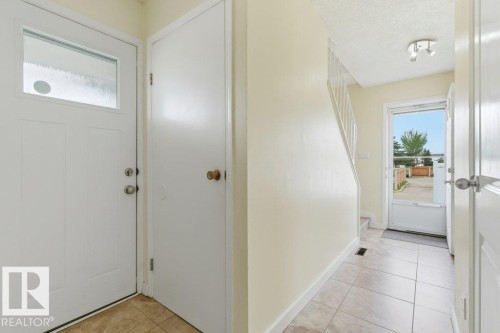 Entryway featuring large format tile flooring, a white paneled front door with a translucent glass insert, and a white interior door - 13279 47 Street, Edmonton, AB - Indoor Photo Showing Other Room