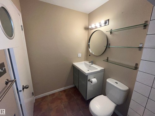 Modern vanity with integrated sink, circular mirror, and multi-bulb light fixture - 306 11340 124, Edmonton, AB 