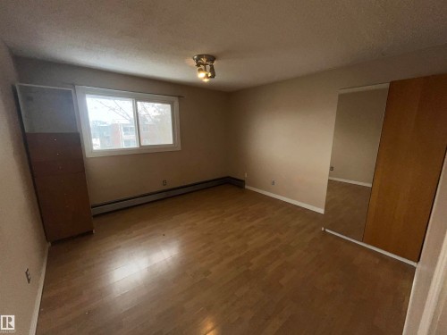 Bedroom featuring wood-finish flooring, a double window, and a ceiling-mounted light fixture - 306 11340 124, Edmonton, AB 