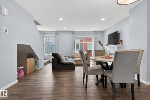 Open-concept living area featuring wood-finish flooring, recessed lighting, and a white fireplace mantel - 62 3305 Orchards Link, Edmonton, AB 