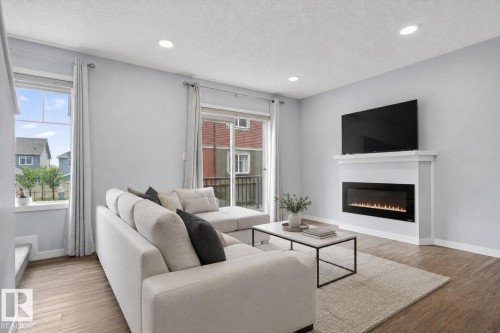 Living area featuring wood-finish flooring, recessed lighting, and light gray wall paint - 62 3305 Orchards Link, Edmonton, AB 