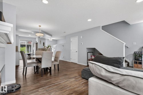 Open-concept living space featuring wood-finish flooring, recessed lighting, and a neutral color palette - 62 3305 Orchards Link, Edmonton, AB 