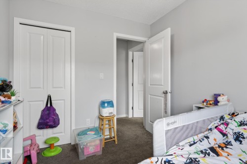 Interior room featuring neutral wall paint, white trim, and dark carpet flooring - 62 3305 Orchards Link, Edmonton, AB 