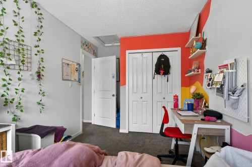 Wall-to-wall carpeting and neutral wall tones define this interior space, featuring a white bi-fold closet door and white paneled interior doors - 62 3305 Orchards Link, Edmonton, AB 