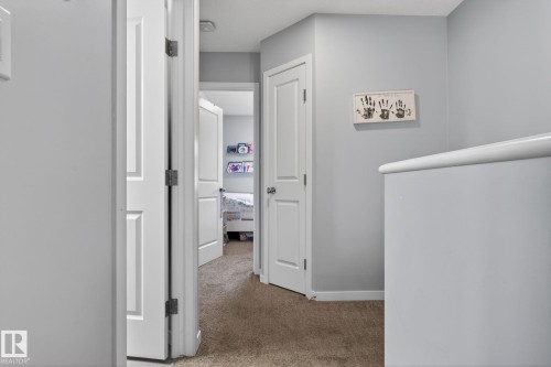 Hallway featuring light gray wall paint, white trim, and carpet flooring - 62 3305 Orchards Link, Edmonton, AB 