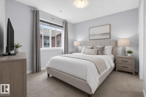 Carpeted bedroom featuring a light gray upholstered bed frame with a channel tufted headboard, two wood-finish nightstands with dark hardware, and a single window with white trim and gray curtains - 62 3305 Orchards Link, Edmonton, AB 