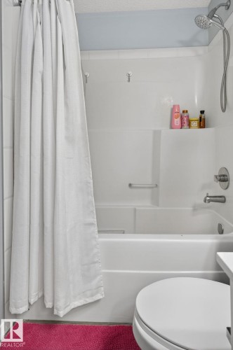 White acrylic bathtub and shower combination with an integrated soap shelf and a chrome shower head with handheld sprayer - 62 3305 Orchards Link, Edmonton, AB 