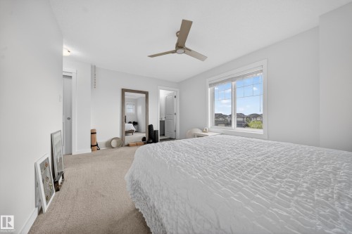 Carpeted interior room featuring a large window, a ceiling fan, and a neutral color palette - 5 903 Crystallina Nera Way, Edmonton, AB 
