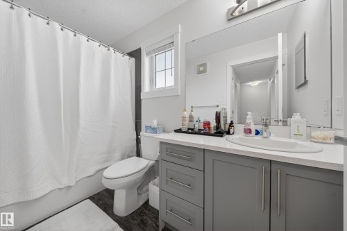 Bathroom featuring a vanity with a white countertop, an undermount sink, and a large mirror - 5 903 Crystallina Nera Way, Edmonton, AB 