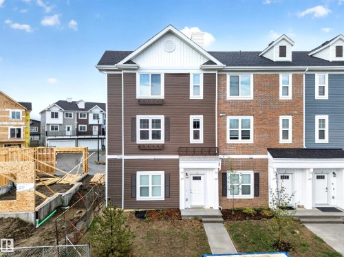 Three-story townhome featuring a brown siding facade with white trim - 5 903 Crystallina Nera Way, Edmonton, AB 
