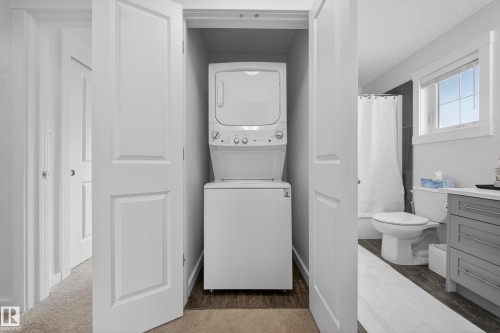Stacked laundry appliances within a dedicated closet, offering convenience - 5 903 Crystallina Nera Way, Edmonton, AB 