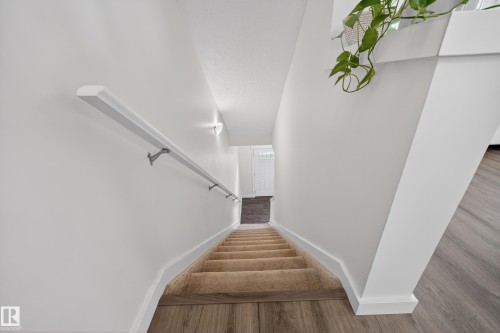 Stairwell featuring carpeted treads, a white handrail, and white baseboards - 5 903 Crystallina Nera Way, Edmonton, AB 