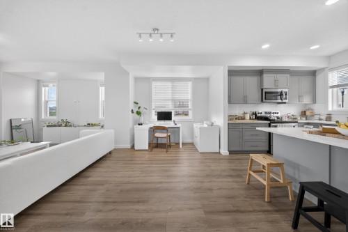 Open-concept living space featuring wood-finish flooring, recessed lighting, and multiple windows with blinds - 5 903 Crystallina Nera Way, Edmonton, AB 