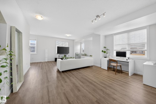 Open-concept living area featuring wood-finish flooring and white walls - 5 903 Crystallina Nera Way, Edmonton, AB 