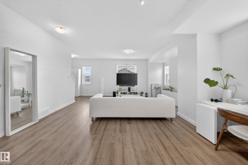 Open concept living space featuring wood-finish flooring, white walls, and recessed lighting - 5 903 Crystallina Nera Way, Edmonton, AB 