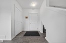 Entryway featuring a solid panel door, wood-finish flooring, white baseboards, and a flush mount ceiling light - 5 903 Crystallina Nera Way, Edmonton, AB 