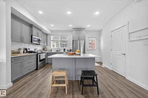 Modern kitchen featuring wood-finish flooring, recessed lighting, and a kitchen island with a light-toned countertop - 5 903 Crystallina Nera Way, Edmonton, AB 