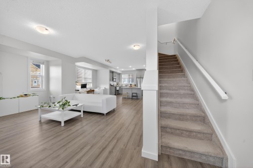 Inviting open-concept living space featuring wood-finish flooring, recessed windows, and white trim - 5 903 Crystallina Nera Way, Edmonton, AB 