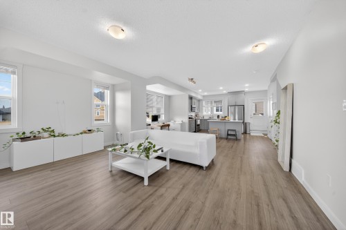 Open-concept living area featuring wood-finish flooring and multiple windows - 5 903 Crystallina Nera Way, Edmonton, AB 