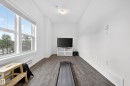 Room featuring large pane windows, wood-finish flooring, white baseboards, and a neutral wall palette - 5 903 Crystallina Nera Way, Edmonton, AB 