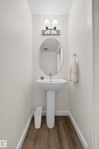 Pedestal sink with chrome faucet, oval mirror, and a two-light vanity fixture - 5 903 Crystallina Nera Way, Edmonton, AB 