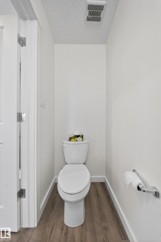 Private water closet featuring wood-finish flooring, white walls, and a white toilet with a chrome toilet paper holder - 5 903 Crystallina Nera Way, Edmonton, AB 
