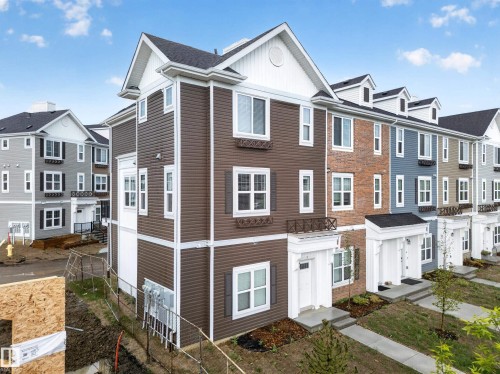 Newly constructed multi-story townhome featuring brown siding, white trim, and dark shutters - 5 903 Crystallina Nera Way, Edmonton, AB 