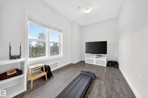 Room with wood-finish flooring, white walls, and a large double-hung window - 5 903 Crystallina Nera Way, Edmonton, AB 
