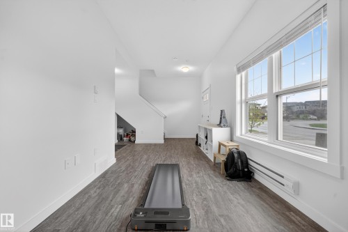 Spacious interior room featuring wood-finish flooring, crisp white walls, and a large multi-pane window providing ample natural light - 5 903 Crystallina Nera Way, Edmonton, AB 