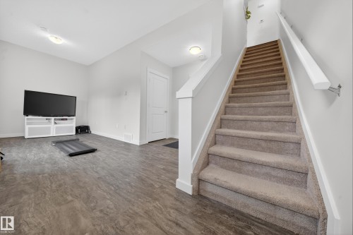 Carpeted staircase with white handrail and wood-finish flooring in an open area - 5 903 Crystallina Nera Way, Edmonton, AB 