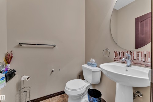 Pedestal sink with chrome faucet, circular wall mirror, and mosaic tile backsplash - 621 Mcdonough Link Link, Edmonton, AB 