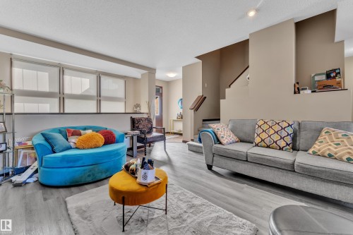 Spacious living area featuring light gray wood-finish flooring, recessed lighting, and a neutral wall palette - 621 Mcdonough Link Link, Edmonton, AB 