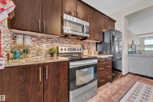 Kitchen featuring dark wood-finish cabinetry with brushed nickel hardware, a stainless steel over-the-range microwave, and a black refrigerator - 621 Mcdonough Link Link, Edmonton, AB 